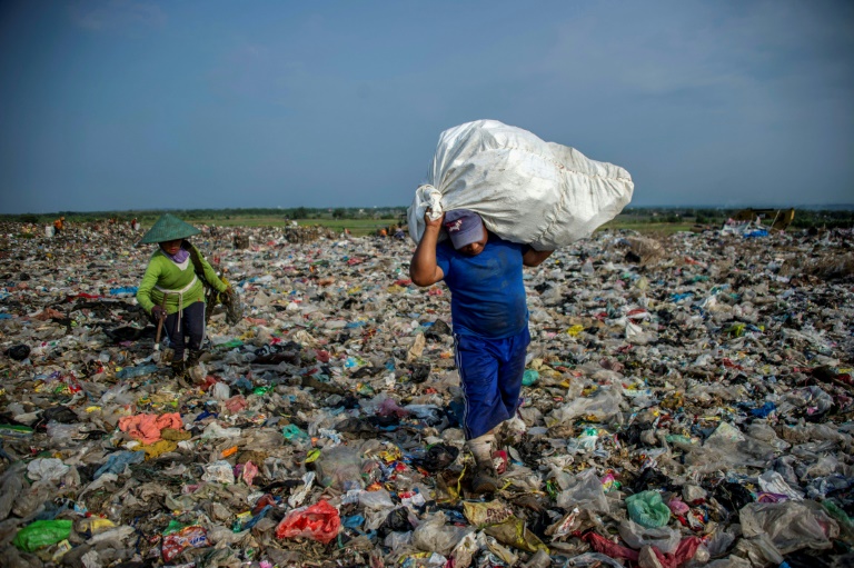 Catadores cercados de lixo plástico em lixão de Sidoarjo, Indonésia