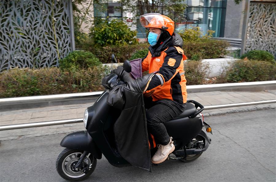 Trabalhador chinês pilota moto com blusa no guidão
