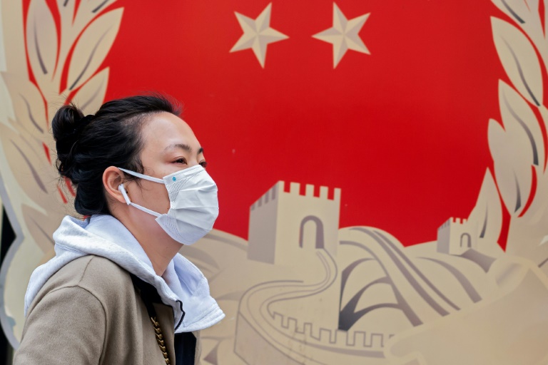 Mulher com máscara caminha por rua de Pequim: Sobre a China, a previsão da Moody’s Analytics é que o PIB tenha contração de 29% neste primeiro trimestre