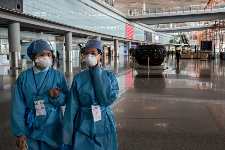 Pessoal com roupa de proteção no aeroporto de Pequim
