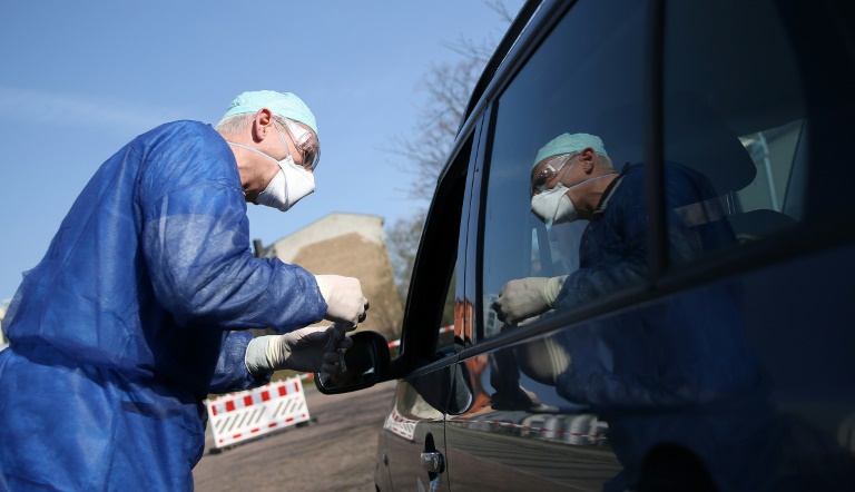O médico Michael Grosse retira amostra de motorista em um centro de teste do novo coronavírus instalado em um estacionamento de Halle em 27 de março de 2020
