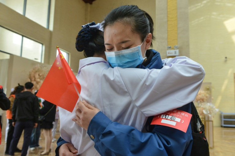 Funcionária de Xiaogan, cidade na província de Hubei, no centro da epidemia de coronavírus, se despede de colega da região de Chongquing em 23 de março de 2020