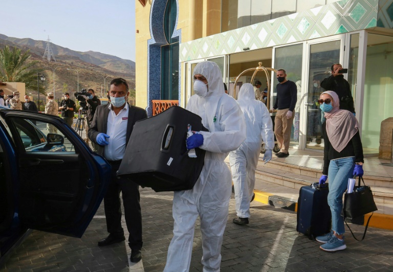 Funcionário ajuda uma hóspede com sua bagagem enquanto ela deixa um resort na Jordânia, onde ficou em quarentena por 14 dias