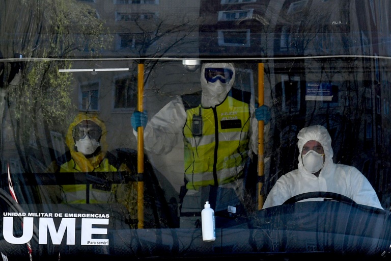 Três membros da Unidade Militar de Emergências (UME) com trajes de proteção em ônibus utilizado para transportar pacientes do hospital Gregorio Marañón ao hospital de campanha do centro de convenções Ifema