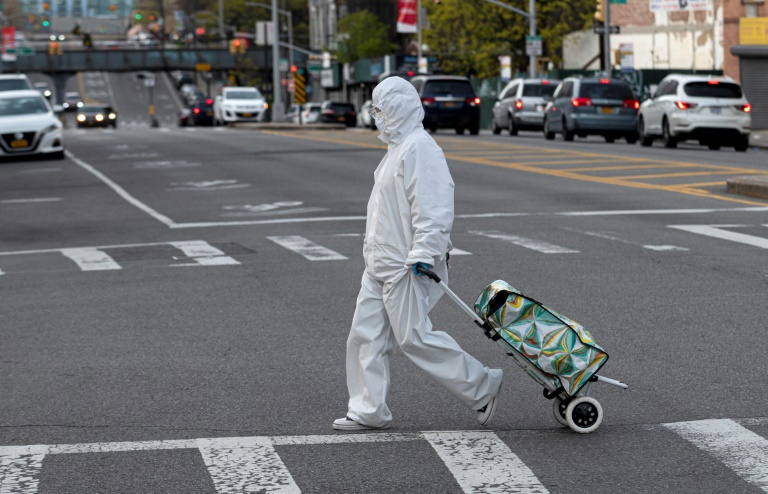 Mulher com traje de proteção caminha por Nova York em 20 de abril de 2020