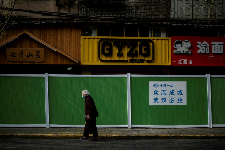 Moradora com máscara caminha por rua de Wuhan, China, no dia 1 de abril de 2020
