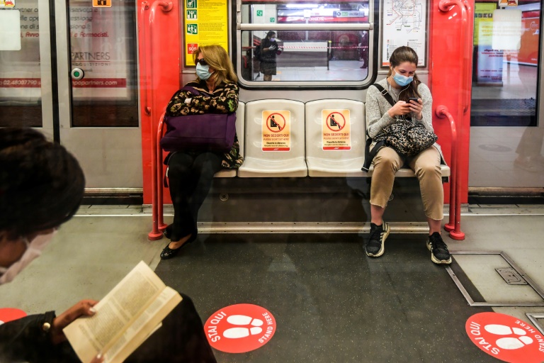 Mulheres de máscara viajam com dois assentos de distância em um vagão do metrô de Milão em 4 de maio de 2020