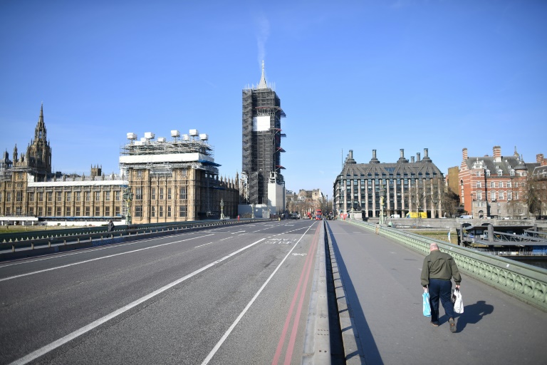 Pedestre cruza Ponte de Westminster de Londres, com o Parlamento ao fundo, em 24 de março de 2020