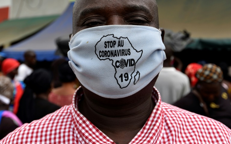 Homem usa máscara com a frase 'Pare o coronavírus' escrita dentro de um mapa da África em uma rua de Abobo, distrito de Abidjan, Costa do Marfim