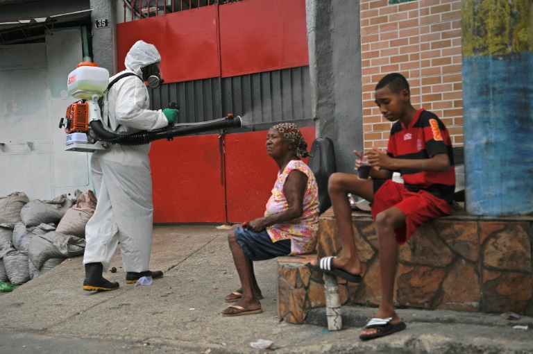 Nesta foto, tirada em 18 de abril de 2020, um voluntário desinfeta uma rua na favela de Babilonia, no Rio de Janeiro