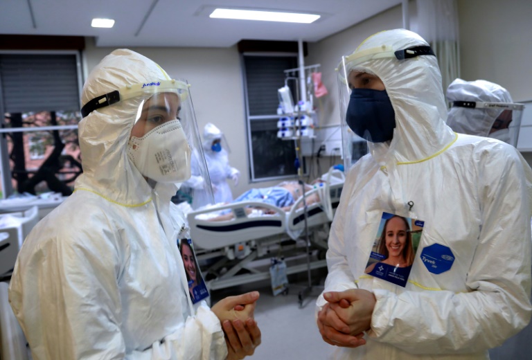 Profissionais de saúde conversam enquanto um paciente infectado com covid-19 é atendido na Unidade de Terapia Intensiva da Santa Casa de Misericórdia de Porto Alegre