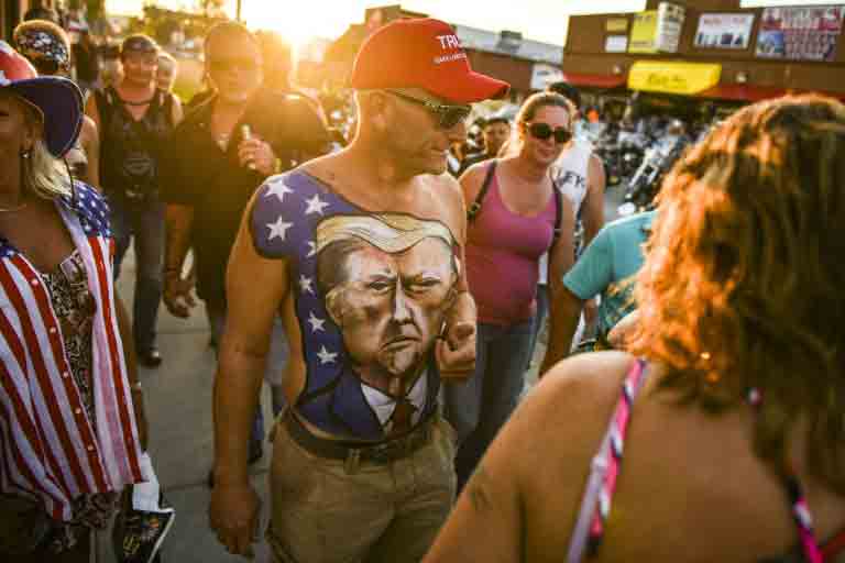 Homem com rosto de Donald Trump pintado no corpo caminha pelas ruas de Sturgis, em Dakota do Sul, em 7 de agosto de 2020 - GETTY IMAGES NORTH AMERICA/AFP