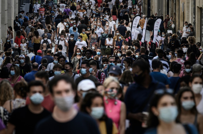 Pedestres, alguns com máscara, caminham por rua comercial em Bordeaux, França -