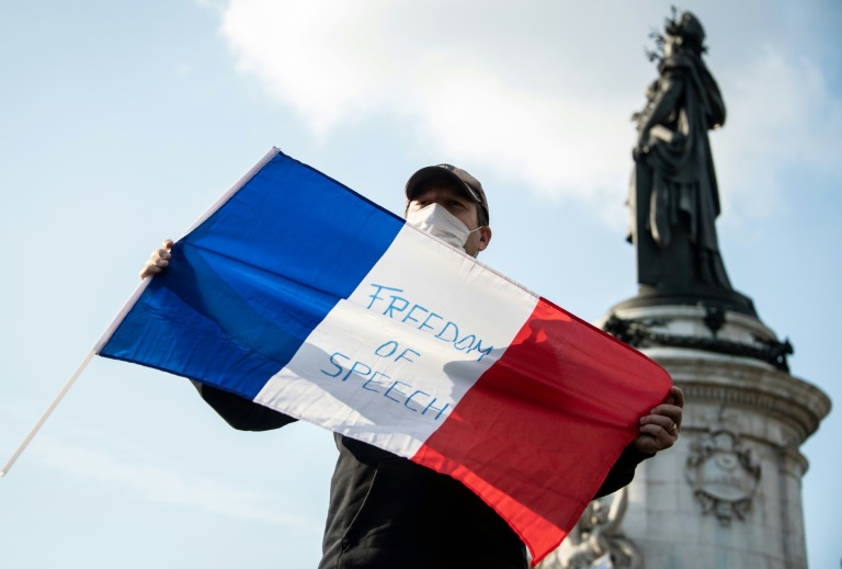 Um homem segura a bandeira da França em Paris, 18 de outubro de 2020 -