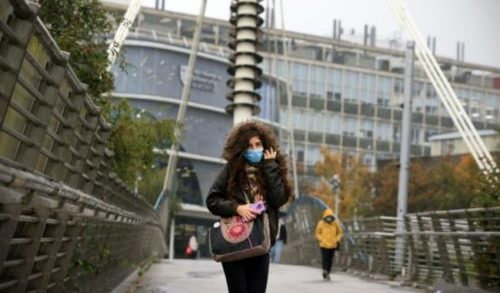 Mulher com máscara caminha perto da Universidade Northumbria, em Newcastle-upon-Tyne, nordeste da Inglaterra, região onde existe uma mutação da covid-19