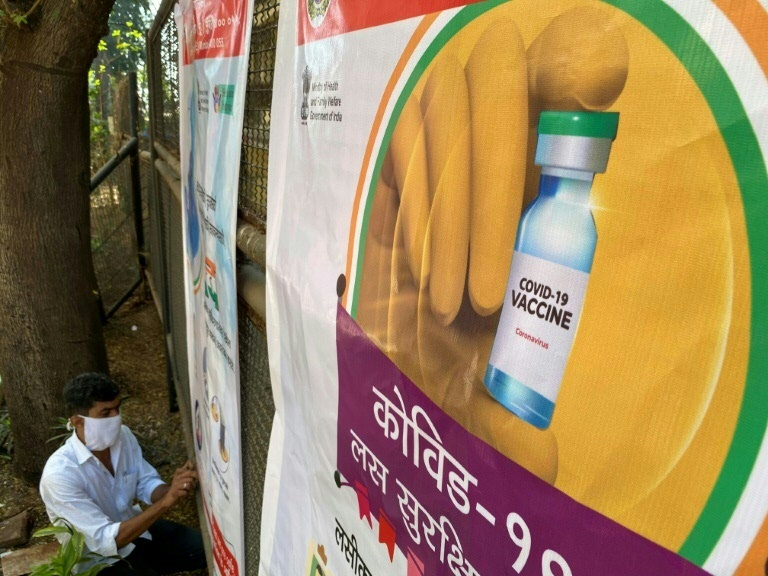 Trabalhador coloca um pôster no centro de vacinação contra o coronavírus em Mumbai