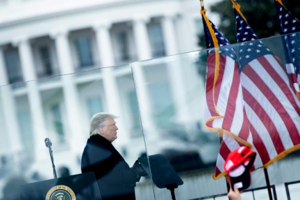 O presidente Donald Trump dirige-se à multidão de seguidores atrás de um vidro à prova de balas do lado de fora da Casa Branca