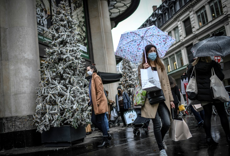 Usando máscaras faciais, pessoas passam pela decoração natalina de uma loja de departamentos em Paris, 24 de dezembro de 2020