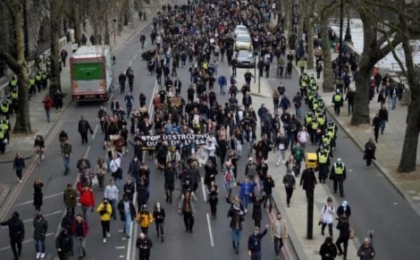 Manifestantes anti-lockdown carregam cartazes e uma faixa durante uma marcha contra as atuais restrições ao coronavírus, no centro de Londres, em 20 de março de 2021