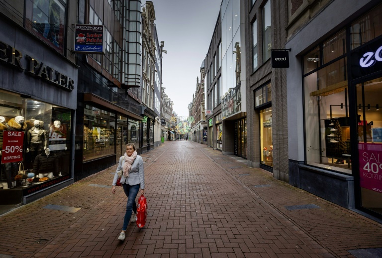 Mulher caminha por uma rua vazia em Amsterdã, em 15 de dezembro de 2020, um dia após o anúncio de um novo confinamento para conter a pandemia