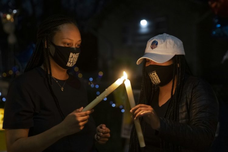 Duas mulheres acendem velas durante uma vigília por Daunte Wright em 17 de abril de 2021 no Brooklyn Center (EUA)