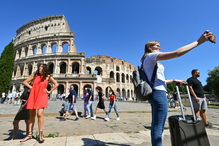 Mulher tira selfie em frente ao Coliseu de Roma, em 12 de junho de 2021