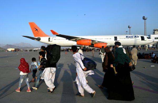 Famílias afegãs passam por aviões no aeroporto de Cabul