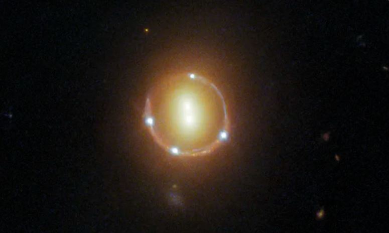 O objeto redondo no centro da fotografia são na verdade três galáxias que aparecem como sete, formando um anel visível em torno das outras.