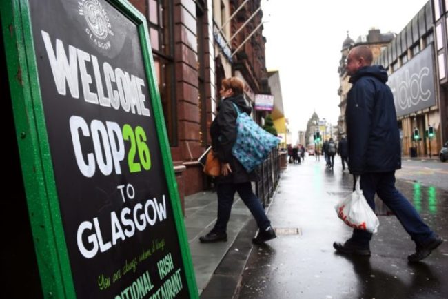 Pessoas entram em um bar passando por uma placa da COP26 no centro da cidade de Glasgow, Escócia, em 29 de outubro de 2021