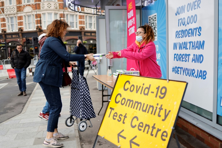 Uma voluntária oferece um kit gratuito de teste rápido da covid-19 em um ponto de distribuição em Hoe Street em Walthamstow, ao norte de Londres, em 30 de dezembro de 2021