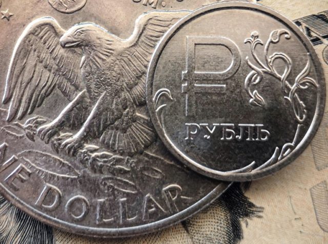 Moeda de rublo russo junto a notas e moeda de dólar