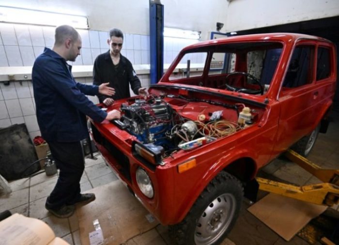O presidente do Lada History Club, Sergei Diogrik (E), e seu assistante Kamil restauram um Lada Niva dos anos 1980, em Togliatti, em 31 de março de 2022