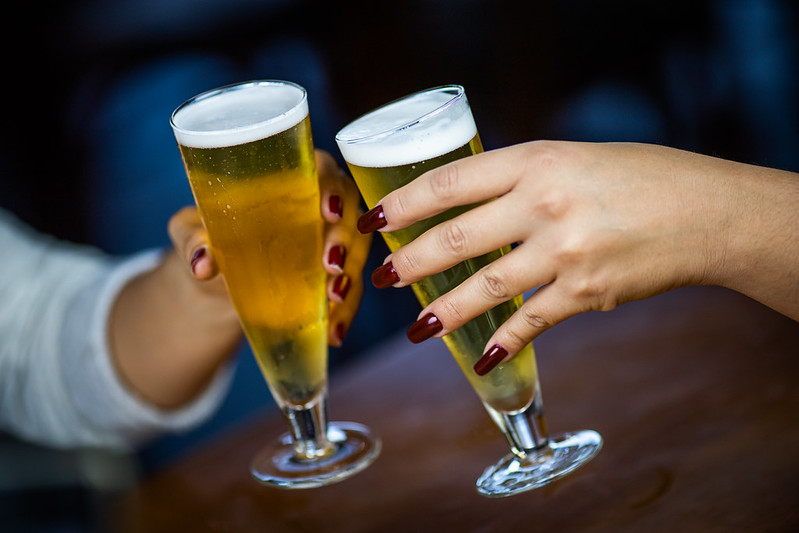 Mãos segurando dois copos de cerveja