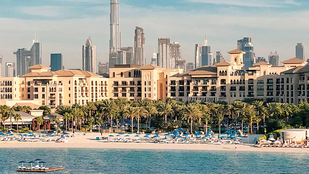 O skyline de Dubai por trás do Four Seasons Jumeirah, hotel de praia que oferece cabanas privativas para quem se proteger do sol (Crédito: Divulgação)