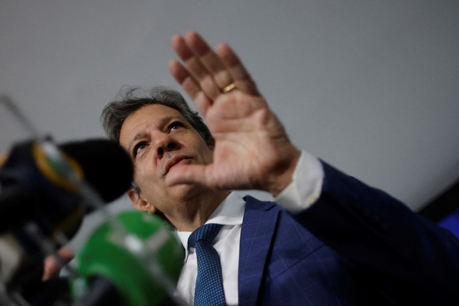 O ministro Fernando Haddad gesticula com uma mão aberta diante microfones em uma coletiva de imprensa