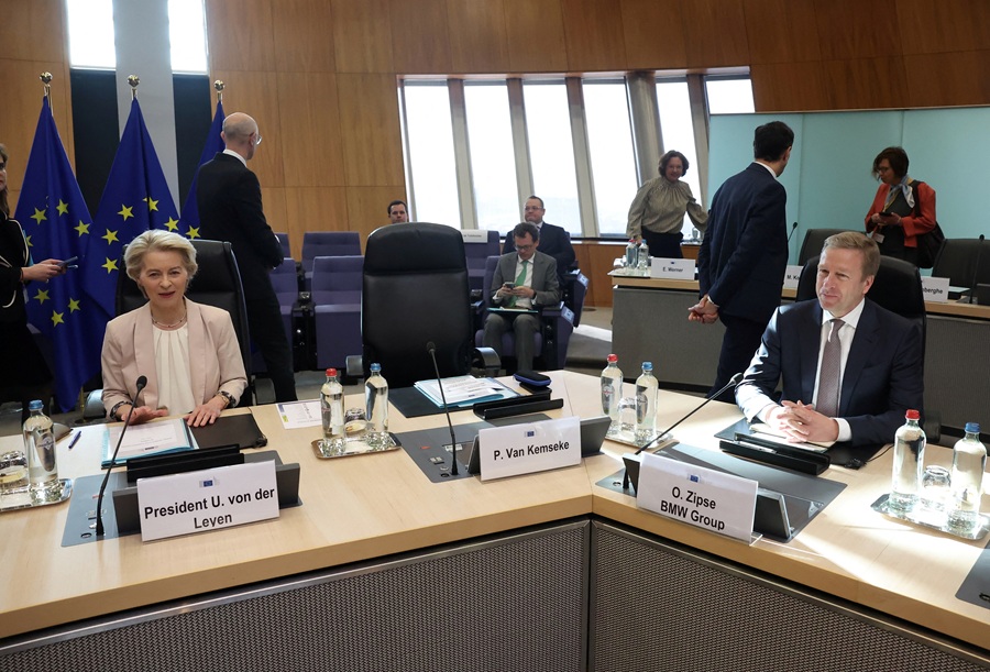 Ursula von der Leyen está em uma mesa de escritório, ao seu lado vemos um executivo da IBM