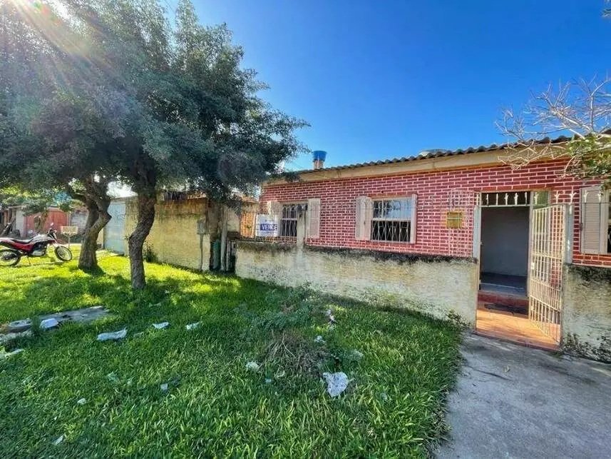 Fotografia da fachada de uma casa que integra um dos leilões. É uma casa vermelha, com um jardim na frente