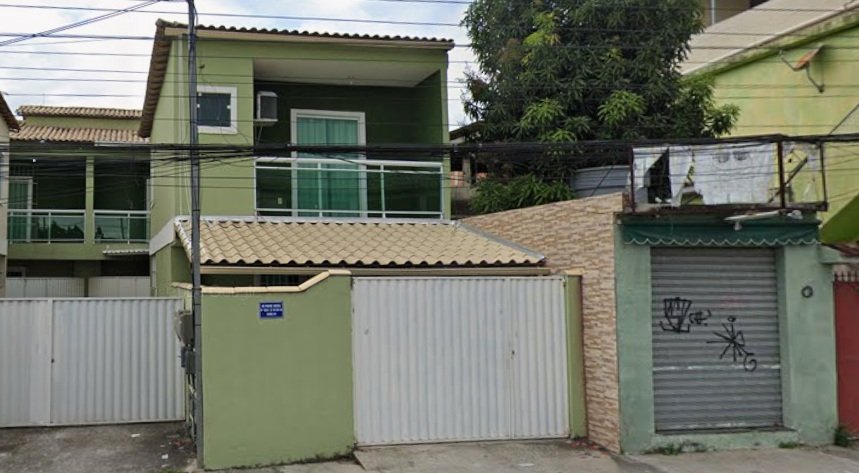 Fotografia da fachada da casa de um dos leilões. É um sobrado pintado de verde, com duas sacadas no segundo andar e duas portas de garagem