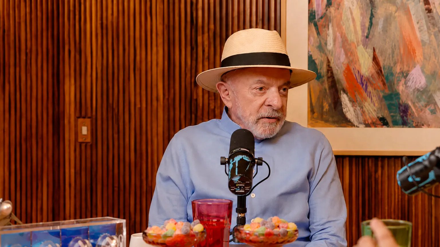 O presidente Luiz Inácio Lula da Silva durante gravação do podcast Inteligência Ltda., vestindo terno escuro, gesticulando enquanto concede entrevista em estúdio.