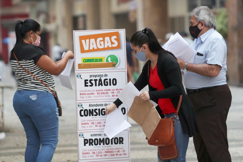 Pessoas deixam currículos em ponto de anúncios de vagas de emprego no centro de São Paulo