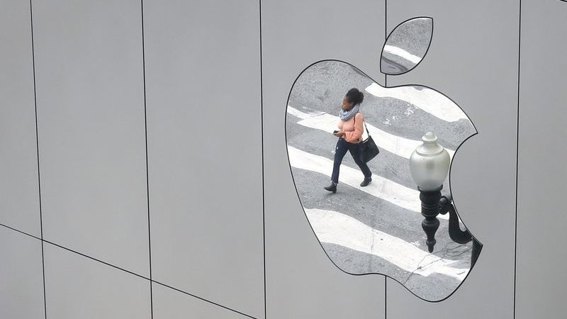 Imagem de pedestre é refletida em logo da Apple em