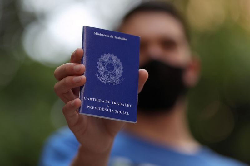 Homem mostra carteira de trabalho ao procurar por oportunidades de emprego em São Paulo