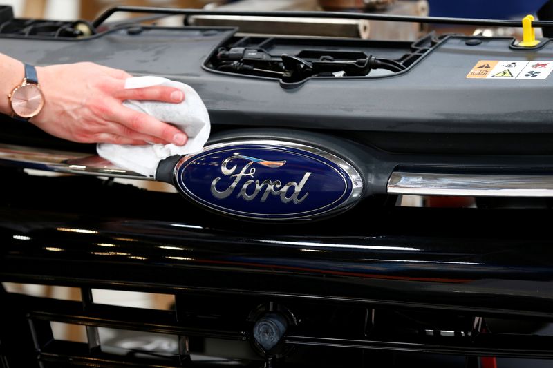 Funcionário limpa o logo da Ford de um modelo da fabricante