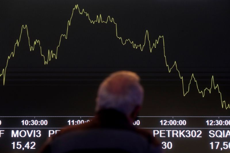 Homem olha para quadro eletrônico mostrando flutuações dos índices de mercado no pregão da Bolsa de Valores B3