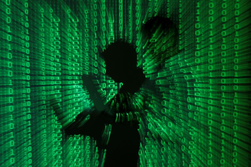 Projeção de códigos binários com homem no centro segurando um laptop