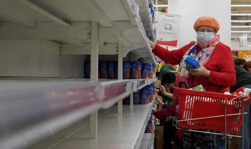 Mulher pega produtos em prateleira de supermercado