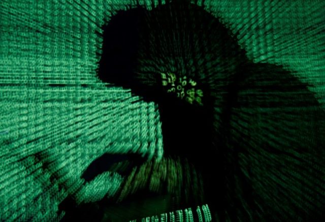 Imagem ilustrativa de homem segurando computador enquanto código cibernético é projetado sobre ele 13/05/2017 REUTERS/Kacper Pempel