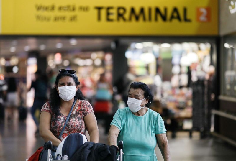 Mulheres usam máscaras de proteção facial no aeroporto de Cumbica