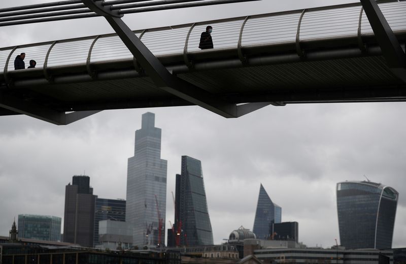 Pessoas atravessam a Millennium Bridge com o distrito financeiro da cidade de Londres visto por trás