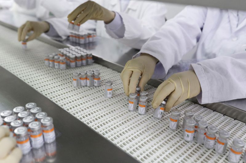Funcionários manuseiam frascos da vacina contra Covid-19 em unidade produtora do Instituto Butantan, em São Paulo